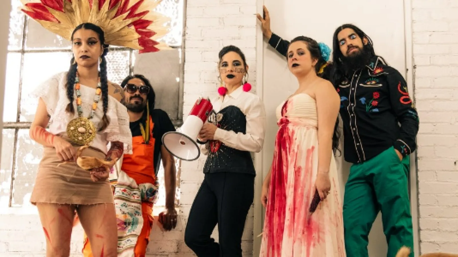 Five people leaning against a wall, wearing colorful costumes