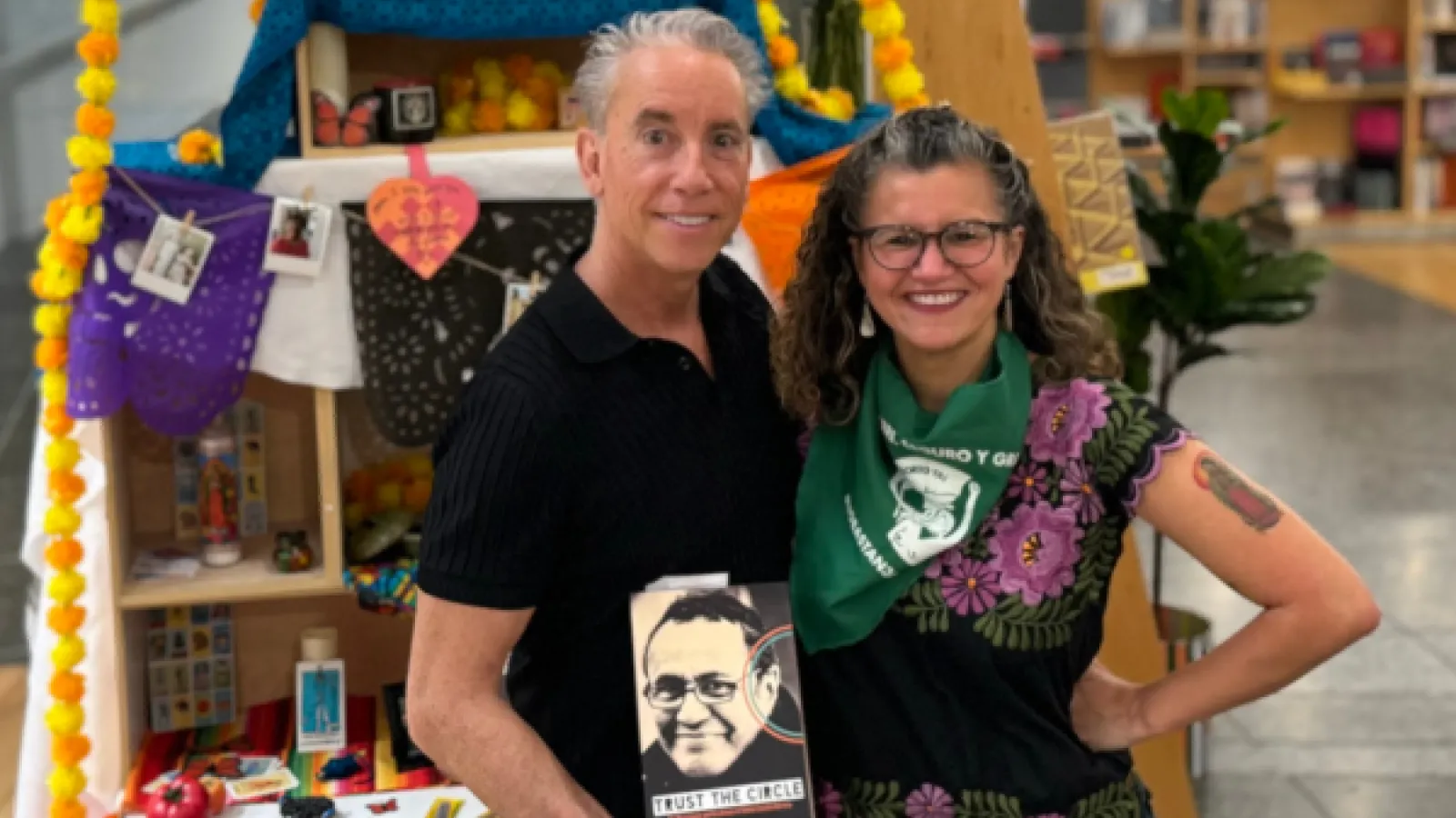 A man and a woman standing in front of an alter for day of the dead