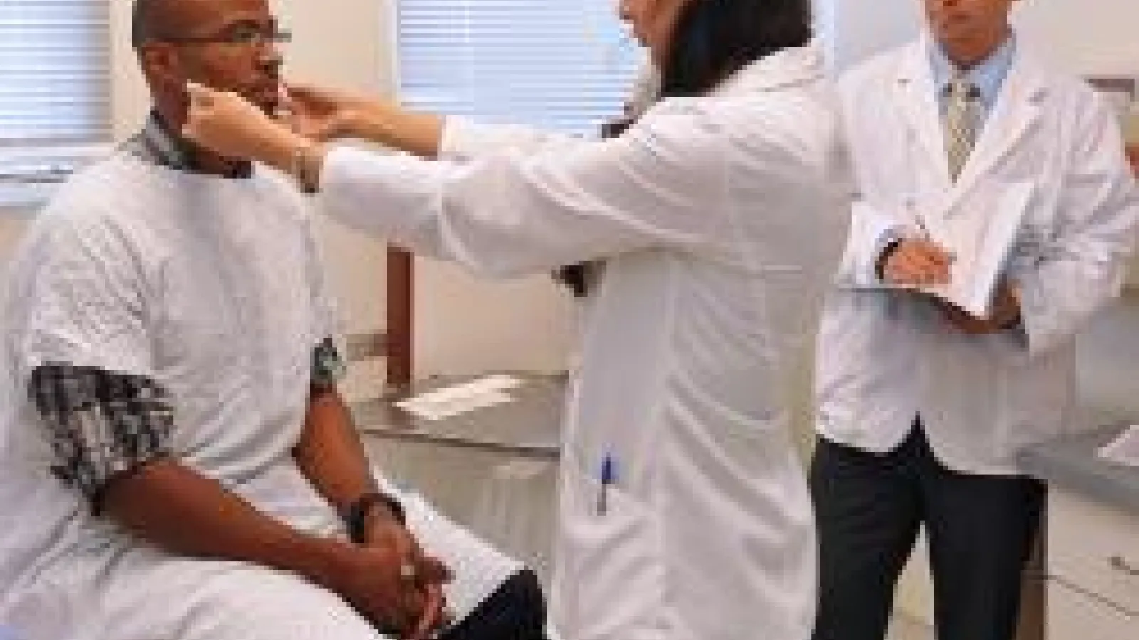 A female doctor is examining the neck of a male patient