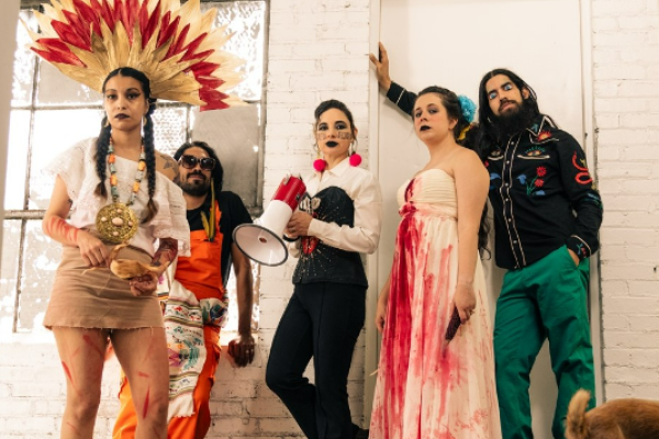 Five people leaning against a wall, wearing colorful costumes