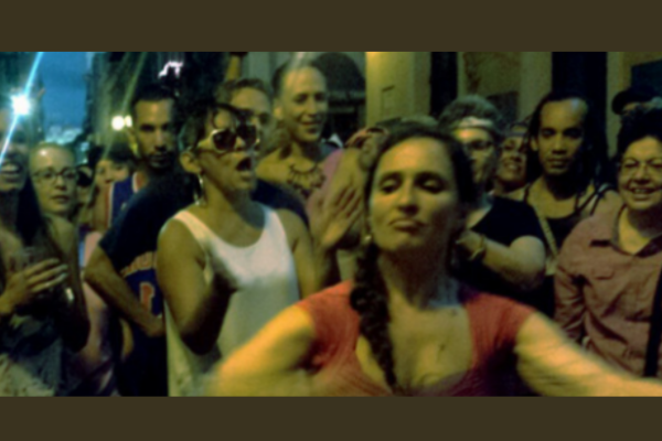 A woman dancing in the foreground surrounded by a cheering crowd