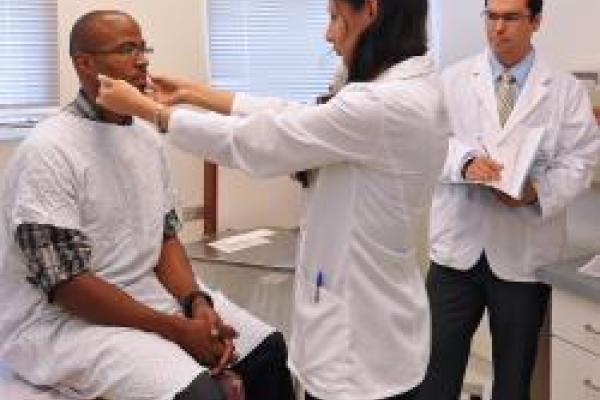 A female doctor is examining the neck of a male patient