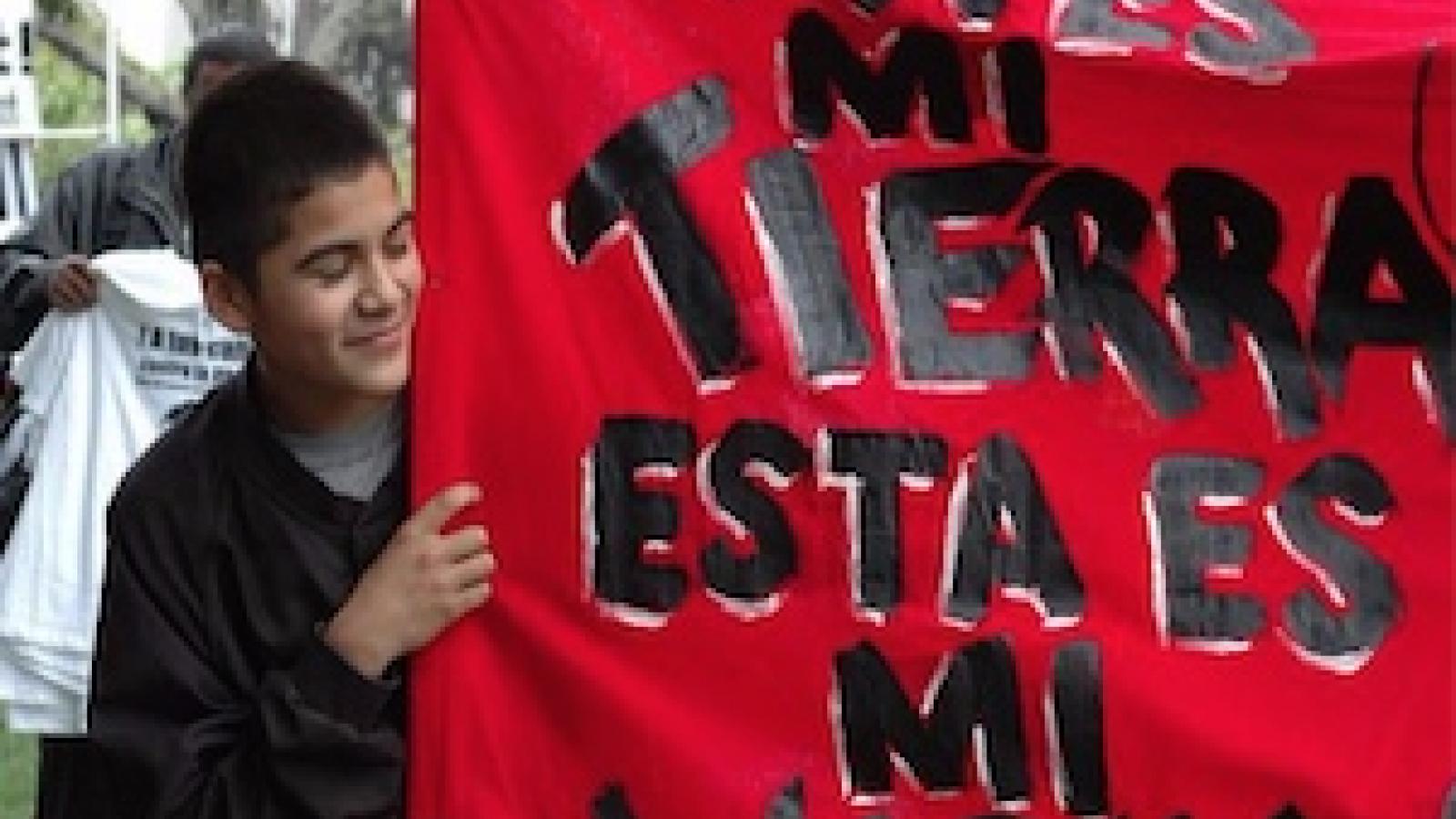Boy holding sign that says Esta Es Mi Tierra Esta Es Mi Lucha